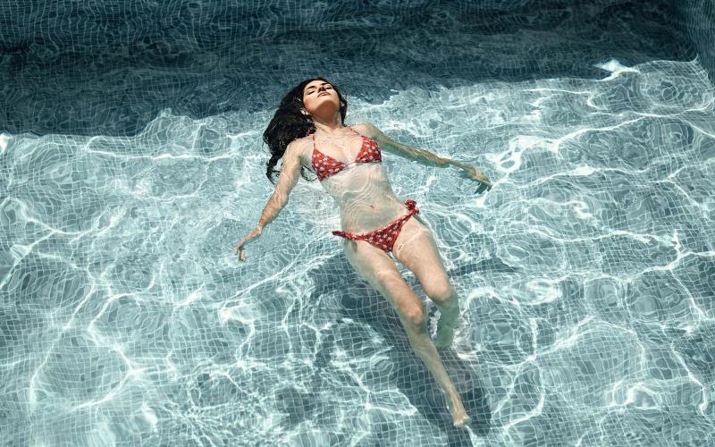 woman floats on her back in swimming pool
